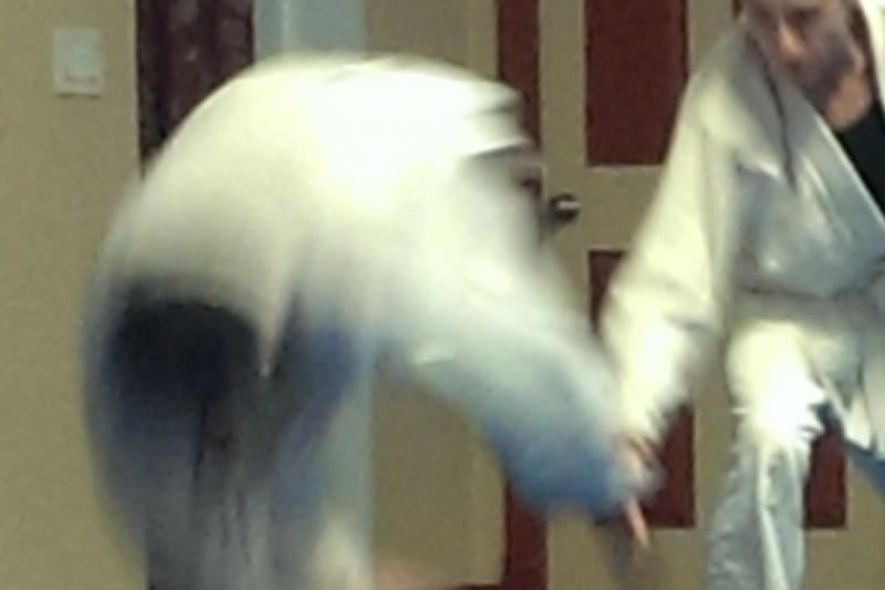 A person bent over as they are about to roll away form another person throwing them.